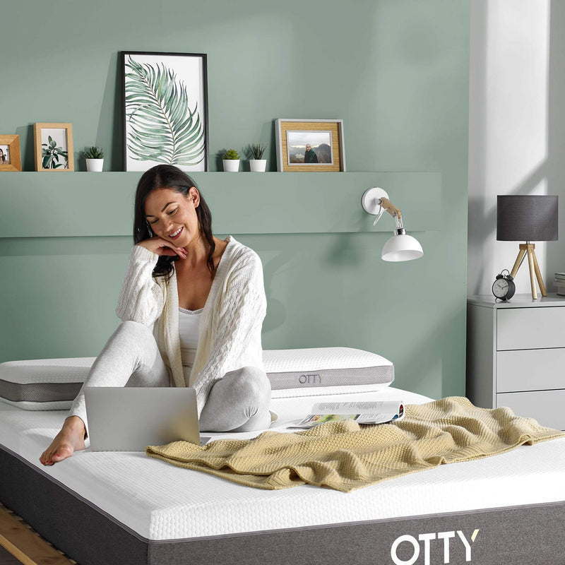 woman sat on her Aura hybrid mattress using a laptop