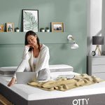 woman sat on her Aura hybrid mattress using a laptop 