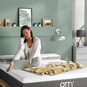 woman sat on her Aura hybrid mattress using a laptop 